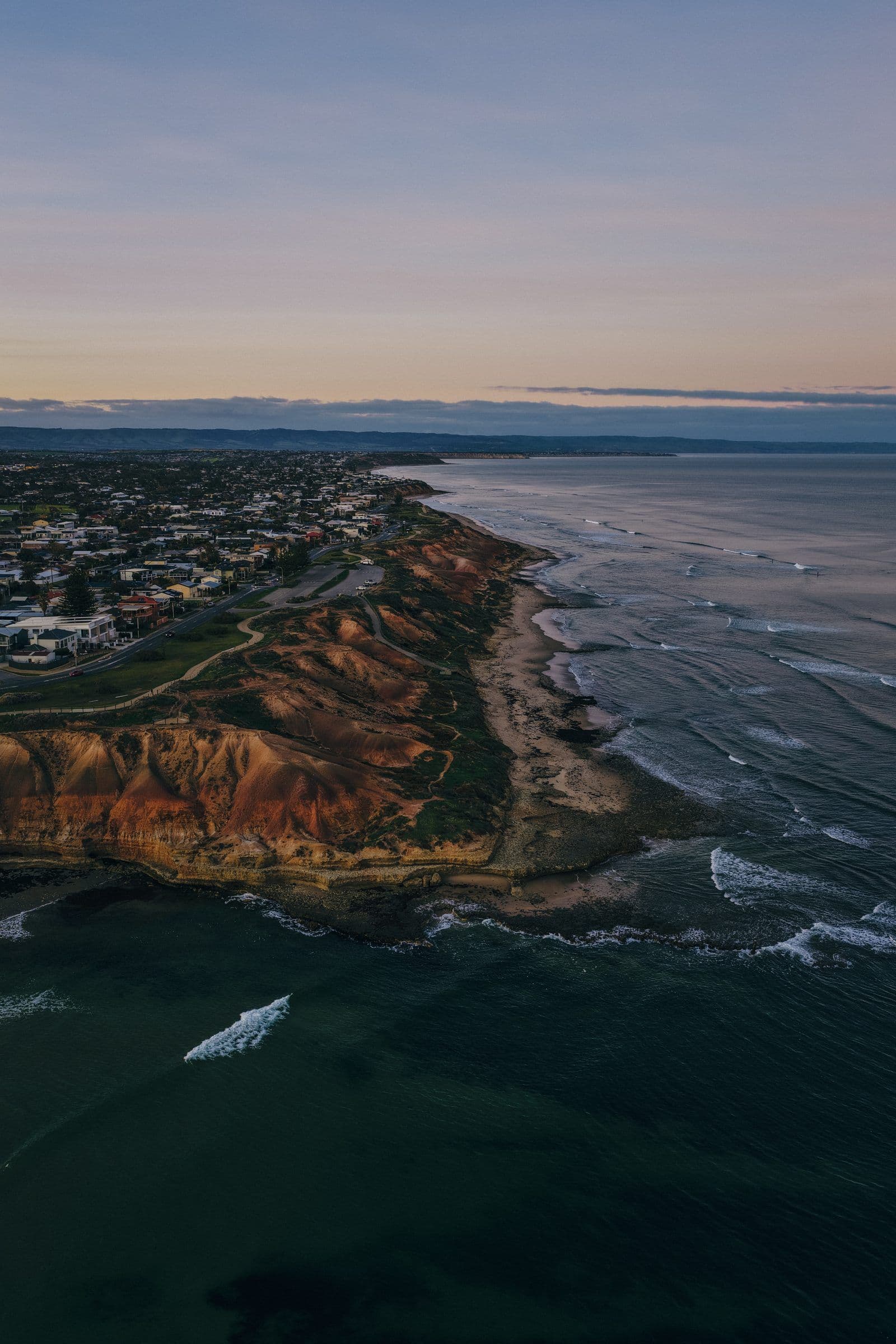 Coastal cliffs glowing at dusk above a seaside town