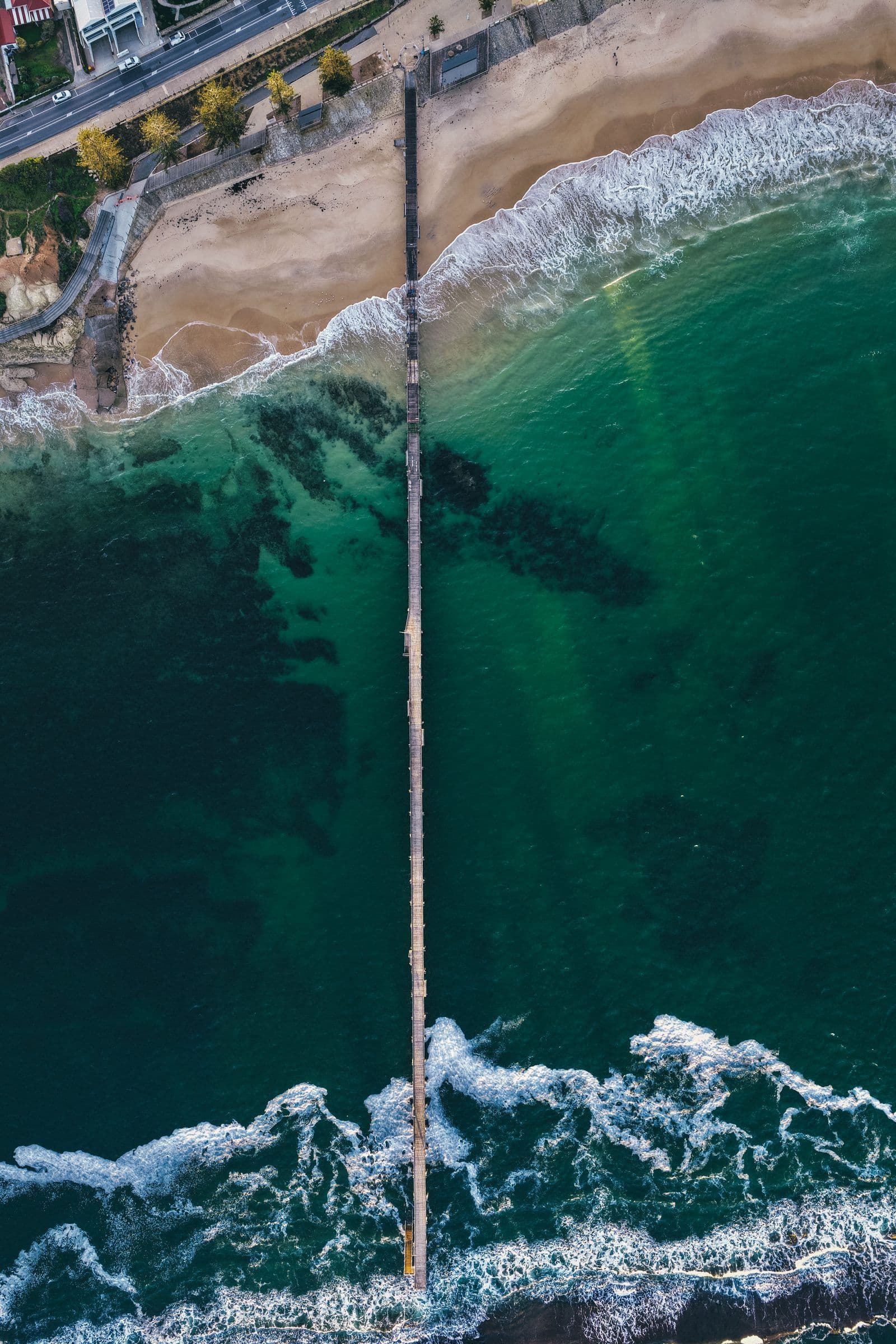 Top-down view of a jetty cutting through breaking waves